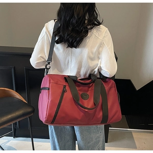 Close-up of a model wearing a burgundy large travel bag with adjustable strap