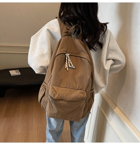 Brown nylon backpack detail showing spacious main compartment and striped zipper pullers