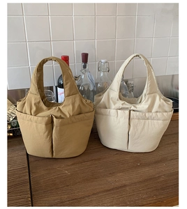 Detail of multi-pocket nylon bucket bags showing wide straps and functional storage design