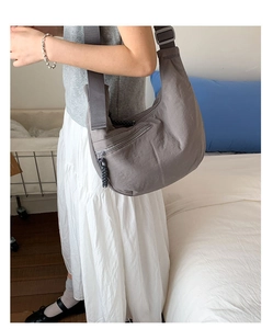 Detail of grey-purple nylon crescent bag with adjustable strap and front zipper pocket