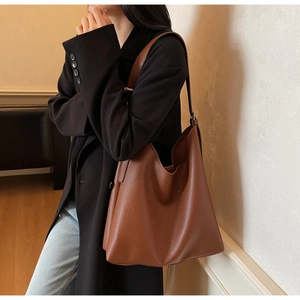Brown lychee-grain leather tote bag showing large capacity and soft texture on model