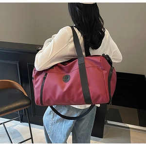 Detail view of the burgundy travel bag featuring durable waterproof fabric and shoulder strap