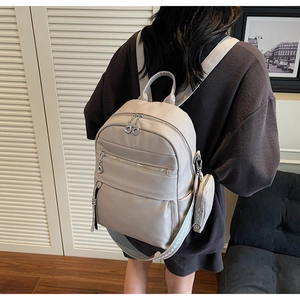 Detail of minimalist beige faux leather backpack with woven straps and small round pouch