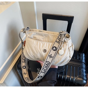 Detail of a beige nylon crossbody bag featuring a branded wide woven shoulder strap