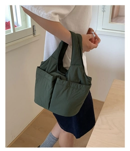 Detail of dark green quilted tote bag featuring two large front pockets for storage