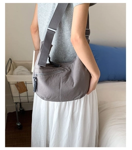 Detailed view of gray nylon dumpling bag featuring wide adjustable strap and zipper pocket