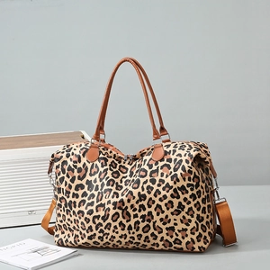 Detail of leopard print travel bag with brown leather handles and wide shoulder strap