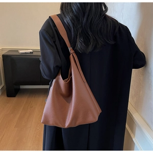 Brown leather hobo bag with adjustable strap worn over a black coat for daily commute