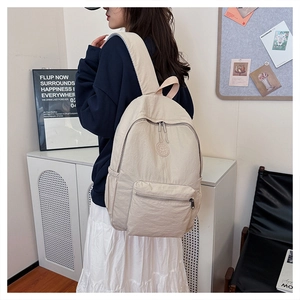 Vue latérale du sac à dos en nylon blanc cassé montrant sa grande capacité sur un modèle