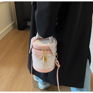 Detail of pink quilted bucket bag with silk scarf handle and golden hardware accents