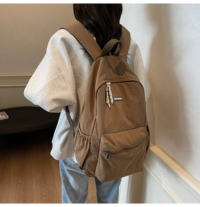 Brown nylon backpack detail showing spacious main compartment and front zipper pocket