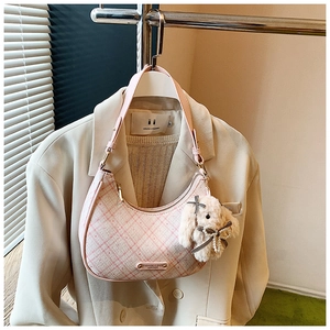 Detailed view of pink plaid crescent bag with plush bunny charm and zipper closure