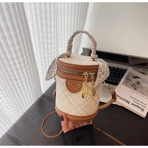 Close-up of diamond quilted bucket bag with silk scarf on handle and golden hardware