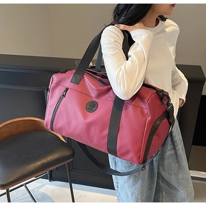 Detailed side view of a large burgundy travel bag with reinforced black nylon straps