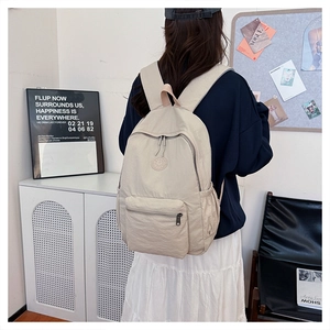 Vue détaillée arrière d'un sac à dos en nylon beige porté par un mannequin en salle