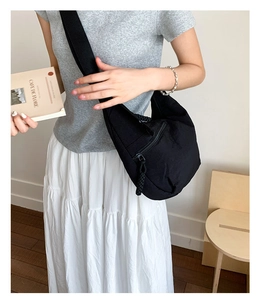 Detailed view of black canvas crossbody bag with thick strap shown in lifestyle setting