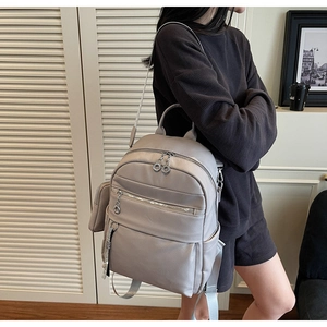 Close-up of gray faux leather backpack featuring multiple zip pockets and silver hardware