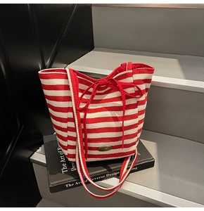 Detail of red and white striped knit tote bag with handmade metal tag and bow closure