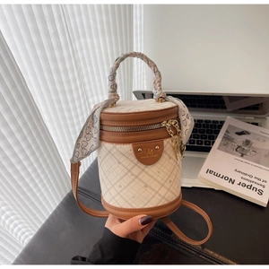 Detail of beige quilted bucket bag with brown trim and silk scarf wrapped handle
