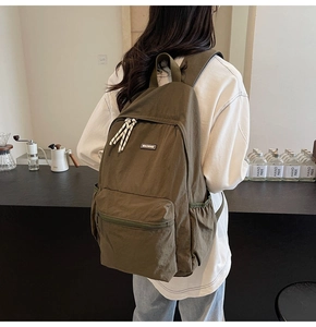 Olive green canvas backpack featuring a spacious front pocket and woven rope zipper details
