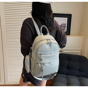 Close-up of a mint green pebbled leather backpack with silver zippers and a mini coin pouch