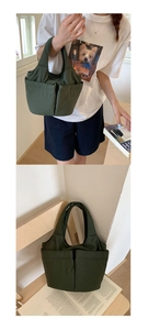 Detail of dark green nylon tote bag with double front pockets on wooden chair and model hand