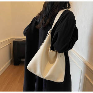 Cream hobo bag in pebbled leather shown on shoulder to display its large capacity size