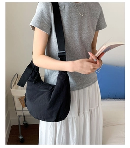 Detail of adjustable strap and front zipper on black nylon crescent crossbody bag