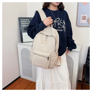 Vue lifestyle d'un sac à dos en nylon crème porté avec focus sur texture et logo