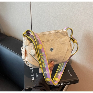 Detail of beige nylon crossbody bag with colorful floral strap and metallic logo