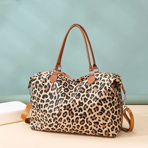 Detail of leopard print travel bag with brown leather handles and adjustable shoulder strap