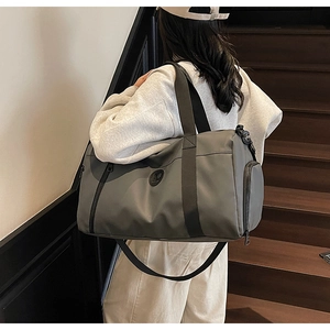 Detail of dark grey travel duffel bag showing the side zipper pocket and waterproof nylon fabric