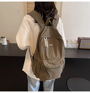 Olive green lightweight nylon backpack shown on model with side view perspective