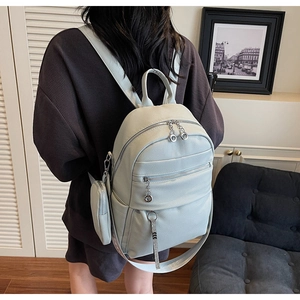 Detail view of light blue leather backpack with double zippers and small coin purse
