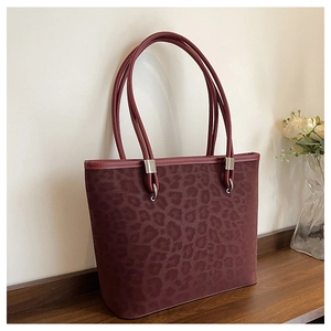 Dettaglio borsa shopper leopardata bordeaux con texture opaca e fibbie in metallo