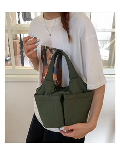 Detail of dark green quilted bucket bag with multi-pocket design shown on a model