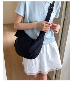 Black crescent dumpling bag shown on a model with an adjustable nylon shoulder strap
