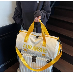 Detail of travel bag showing yellow handles and brand logo on white fabric surface