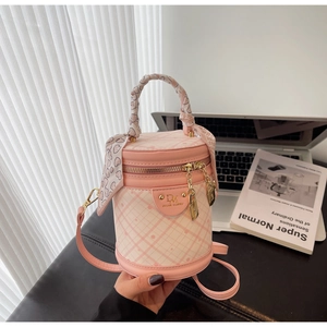 Detail of a quilted bucket bag with pink heart scarf wrap on handle and golden hardware