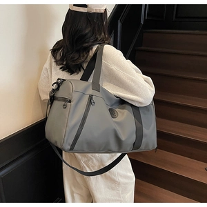 Detail of dark grey travel bag showing multiple zipper pockets and nylon material