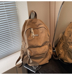 Detail view of khaki school backpack with MACHUGE label and side storage pockets