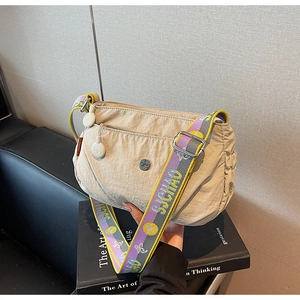 Detail of beige nylon crossbody bag with colorful woven strap and metal zipper