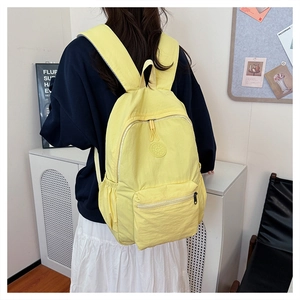 Détail d'un sac à dos en nylon jaune avec de larges bretelles et un tissu imperméable