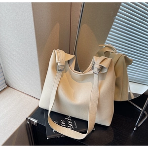 Detail of creamy white pebble grain leather tote bag with silver adjustable buckle strap