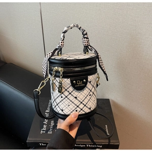 Detail of checkered bucket bag with polka dot scarf and gold zipper on design books