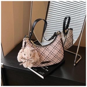 Close-up of retro pink plaid crescent bag with a cute plush bunny charm and leather strap