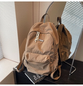 Detail view of the durable nylon fabric and front zipper pocket of the khaki backpack