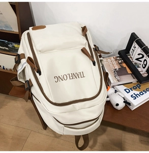 Detail view of cream casual backpack with brown leather accents and multi-pocket design
