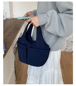 Close-up of a navy blue quilted nylon tote bag with dual front utility pockets