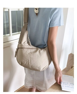 Detail view of beige nylon crossbody bag with textured fabric and woven zipper puller